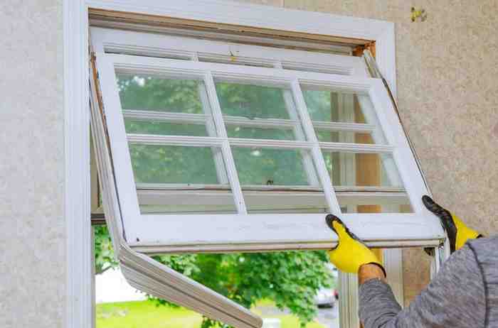 Worker removing old multi-pane window during a home renovation.